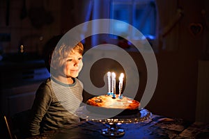 Little kid boy celebrating his birthday and blowing candles on cake