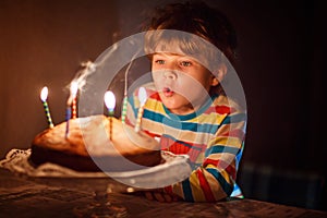 Little kid boy celebrating his birthday and blowing candles on cake