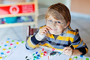 Little kid boy drawing with colorful watercolors indoors