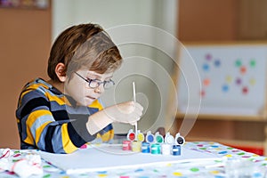 Little kid boy drawing with colorful watercolors indoors