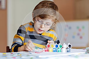 Little kid boy drawing with colorful watercolors