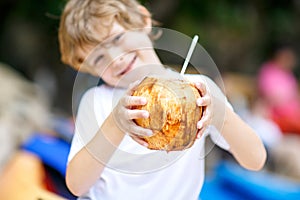 Little kid boy drinking coconut juice on tropical beach