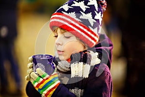 Little kid boy drinking hot chocolate on Christmas market
