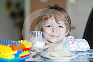 Little kid boy drinking milk and playing with construction block