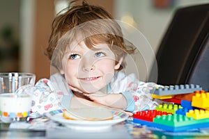 Little kid boy drinking milk and playing with construction block