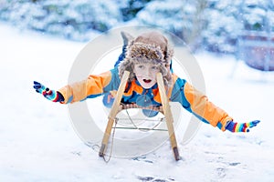 Little kid boy enjoying sleigh ride in winter