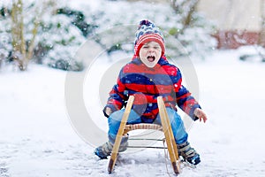 Little kid boy enjoying sleigh ride in winter