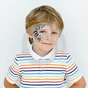 Little kid boy with face painted with a spider web