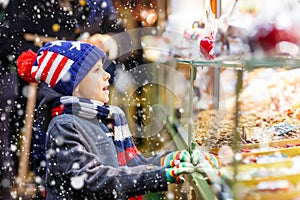 Little kid boy with gingerbread and sweets stand on Christmas market