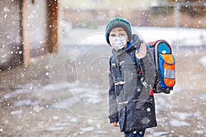 Little kid boy with glasses wearing medical mask on the way to school after lockdown. Child backpack satchel. Schoolkid