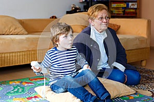 Little kid boy and grandmother playing video game