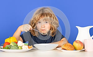 Little kid boy have a dinner. Child eating soup. Young boy with spoon eating soup. Cute healthy hungry child boy eating