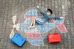 Little kid boy having fun with with airplane picture drawing with colorful chalks on asphalt. Child painting with chalk