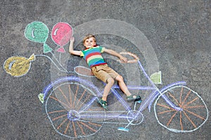 Little kid boy having fun with bicycle chalks picture on ground