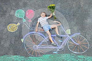 Little kid boy having fun with bicycle chalks picture on ground