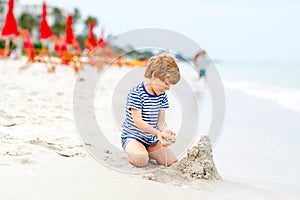 Little kid boy having fun with building sand castles