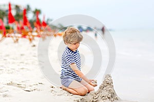 Little kid boy having fun with building sand castles