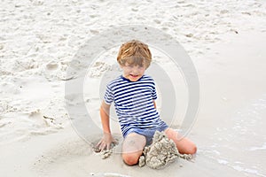 Little kid boy having fun with building sand castles