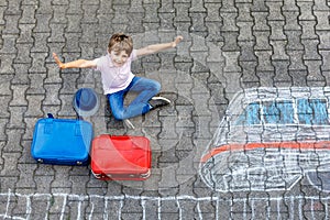 Little kid boy having fun with fast train picture drawing with colorful chalks on asphalt