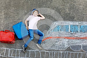 Little kid boy having fun with fast train picture drawing with colorful chalks on asphalt