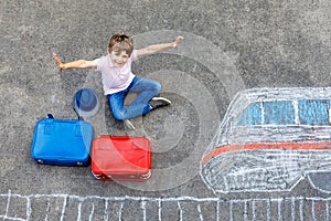 Little kid boy having fun with fast train picture drawing with colorful chalks on asphalt