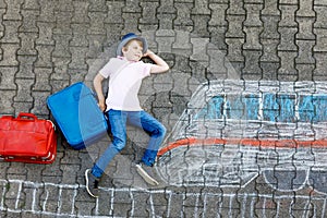 Little kid boy having fun with fast train picture drawing with colorful chalks on asphalt