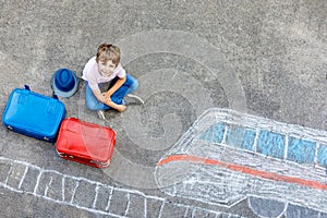 Little kid boy having fun with fast train picture drawing with colorful chalks on asphalt