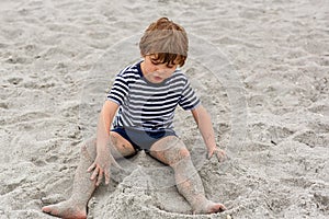 Little kid boy having fun on tropical beach