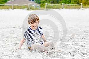 Little kid boy having fun on tropical beach