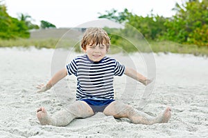 Little kid boy having fun on tropical beach