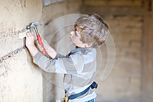 Little kid boy helping with toy tools on construction site. Funny child of 6 years having fun on building new family