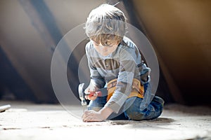 Little kid boy helping with toy tools on construction site. Funny child of 6 years having fun on building new family