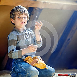 Little kid boy helping with toy tools on construction site. Funny child of 6 years having fun on building new family