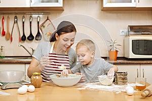 Little kid boy helps mother to cook ginger biscuit. Happy family mom and child in weekend morning at home. Relationship.