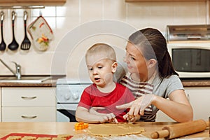 Little kid boy helps mother to cook ginger biscuit. Happy family mom and child in weekend morning at home. Relationship.