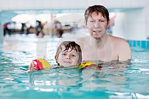 Little kid boy and his father swimming in an indoor pool