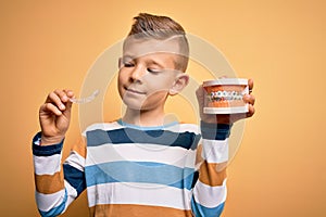 Little kid boy holding professional orthodontic denture with metal braces and removable invisible aligner