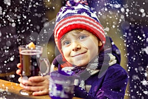 Little kid boy with hot chocolate on Christmas market