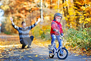 Little kid boy learning moving on bicycle. His father teaching his son biking. Happy man and child. Active family