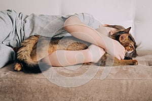 Little kid boy lying on the couch and hugging his fluffy tail red cat kitten of somaly breed