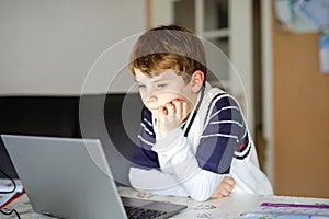 Little kid boy making school homework on computer notebook. Happy healthy child searching information on internet. New