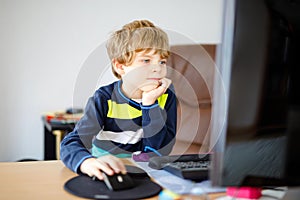 Little kid boy making school homework on computer notebook. Happy healthy child searching information on internet. New