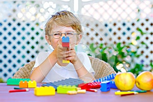 Little kid boy playing with colorful plastic blocks