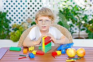 Little kid boy playing with colorful plastic blocks