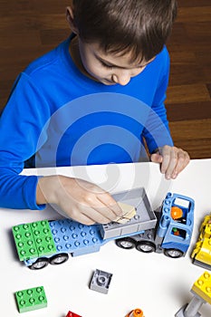 Little kid boy playing with colorful plastic blocks indoor