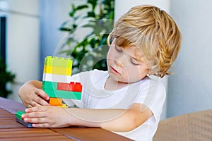 Little kid boy playing with plastic blocks