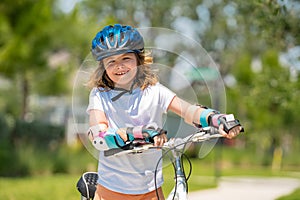 Little kid boy riding a bike in summer park. Children learning to drive a bicycle on a driveway outside. Kid riding