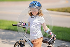 Little kid boy riding a bike in summer park. Children learning to drive a bicycle on a driveway outside. Kid riding
