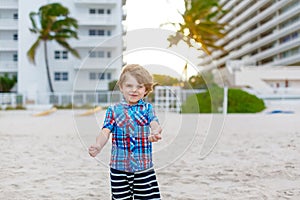 Little kid boy running on the beach of ocean