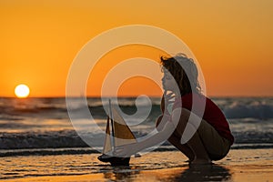 Little kid boy sailing toy ship on sea water. Summer vacation with kids. Kid dreaming about sailing. Concept of